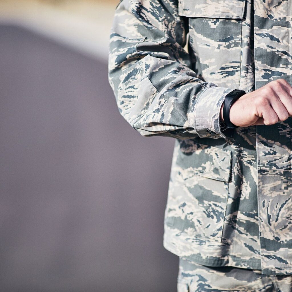 Man in military fatigues checking smartwatch that is part of his everyday carry items.