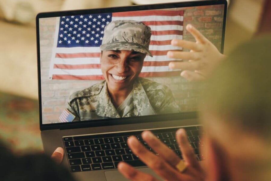 Military mom in fatigues chatting with her family on a video call.