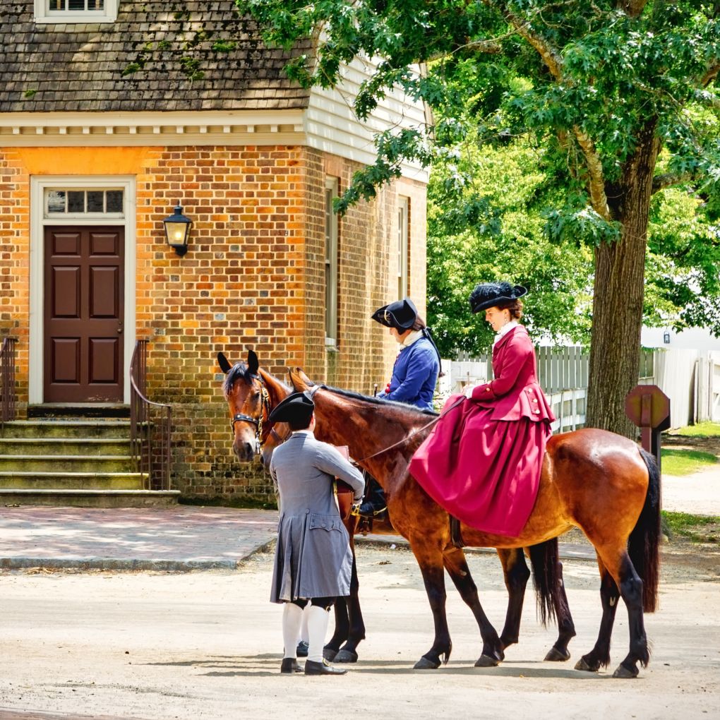 Williamsburg, Virginia / USA – June 30, 2016: Citizens of Colonial Williamsburg, in period clothing, meet in the street on horseback.