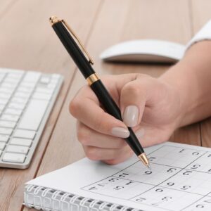 Woman solving sudoku puzzle at table, closeup