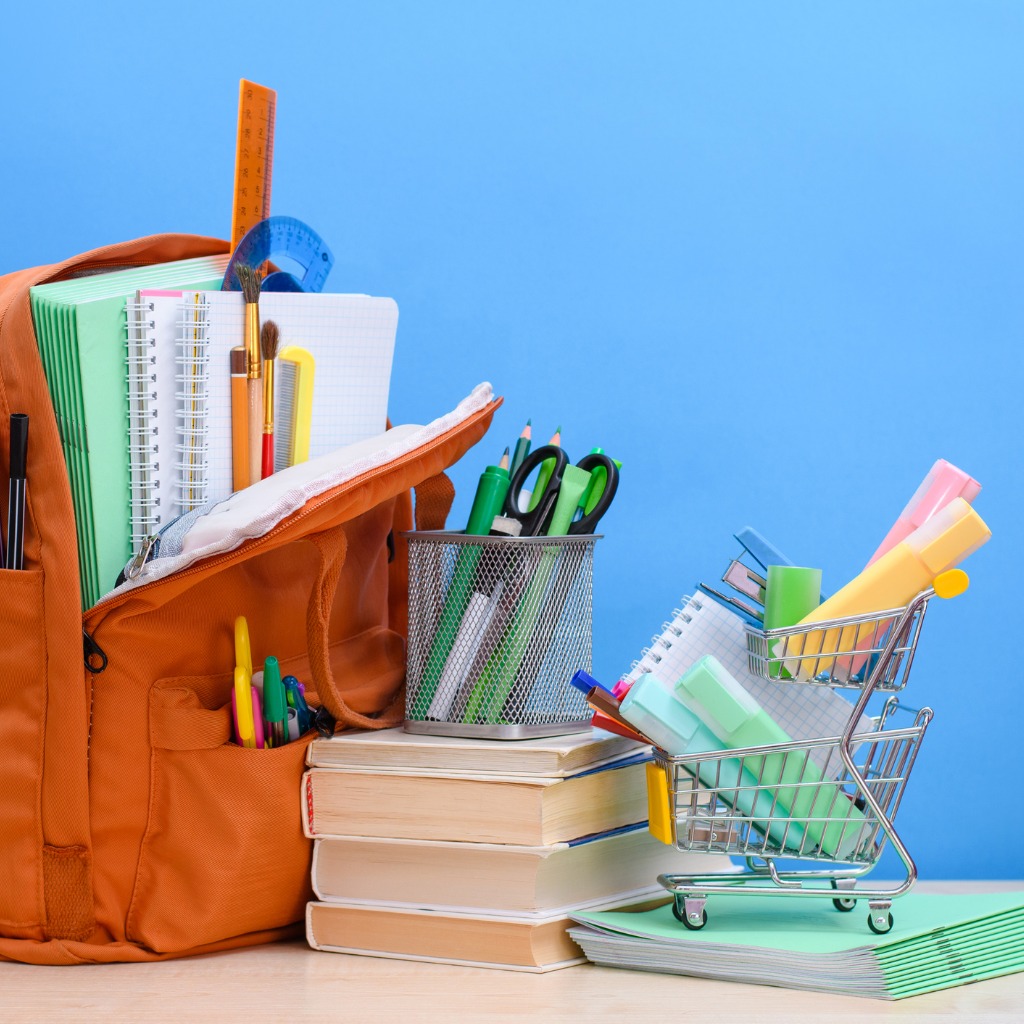 Image of school supplies next to a tiny shopping cart suggesting back-to-school shopping.