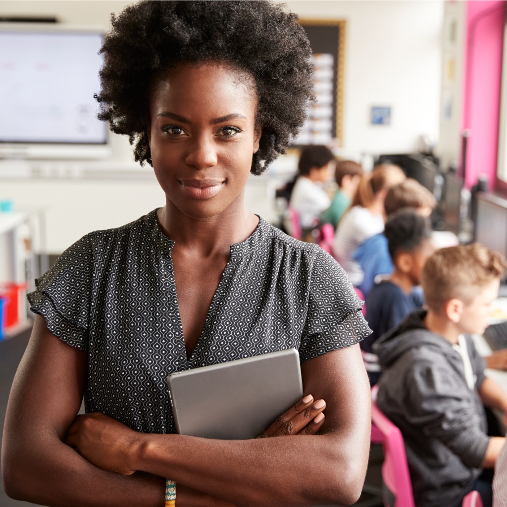 Pretty young Black teacher holding a tablet she uses for classroom automation.