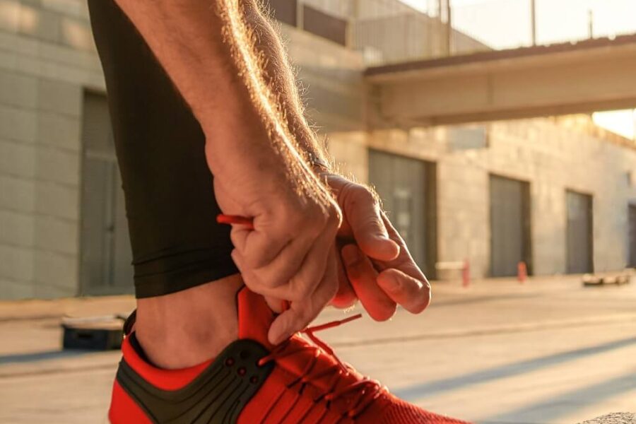 Photo of a man tying red and black running shoes.