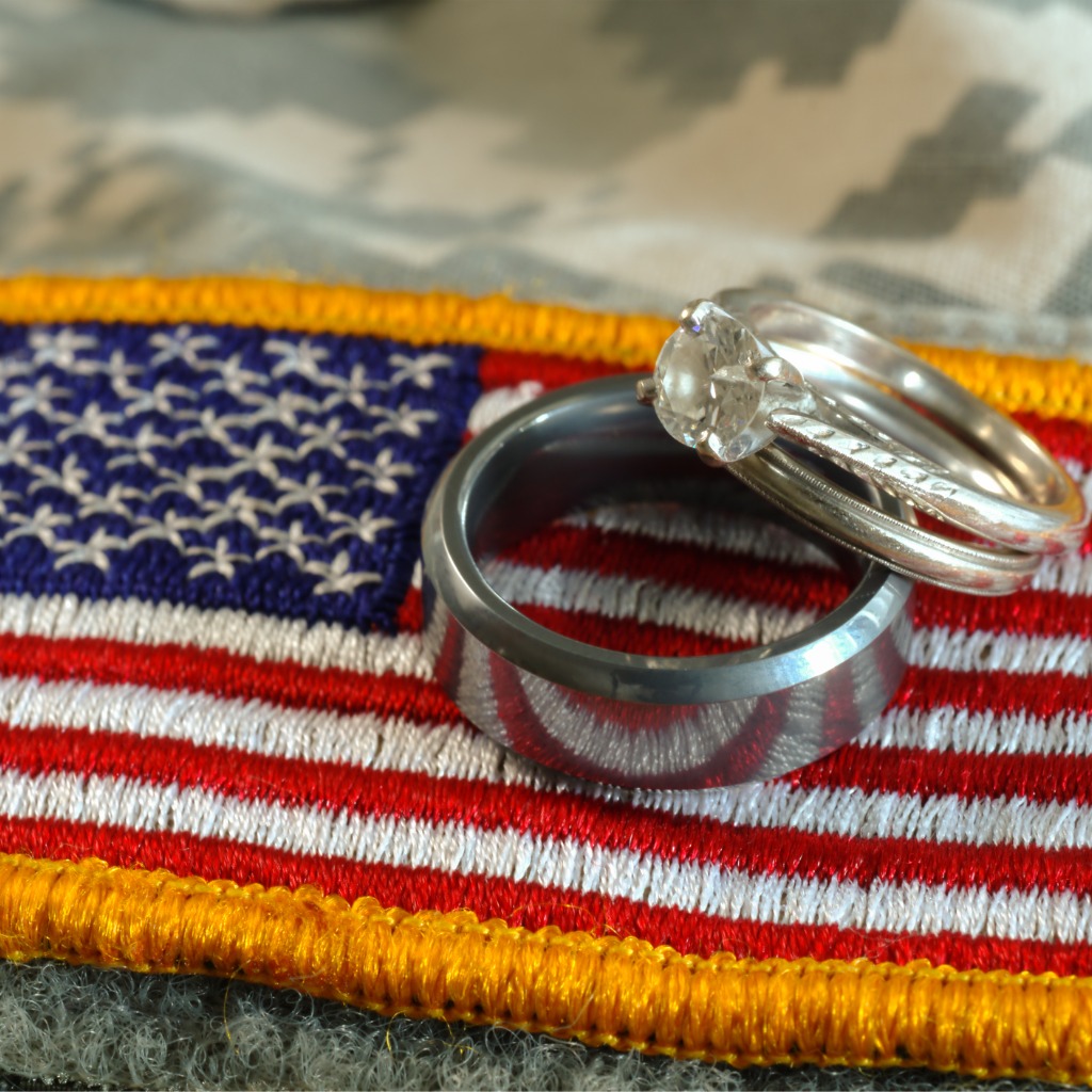 Photo of a pair of wedding rings resting on a piece of camo clothing with a U.S. flag patch.
