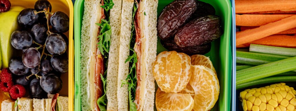 Photo of school lunch with sandwich, veggie sticks, and fruit representing back-to-school shopping for school lunch supplies and dorm living.