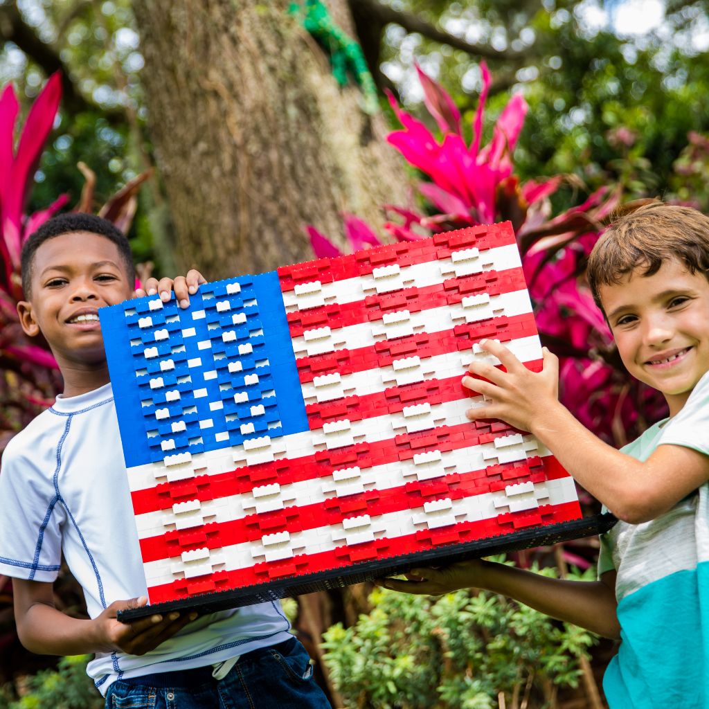 Two young boys holding an American flag made of LEGOs.