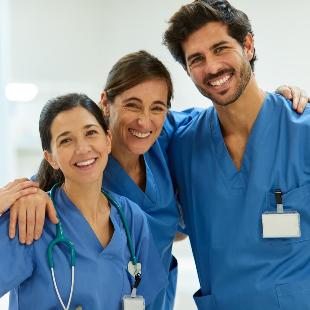 Three nurses facing the camera, hugging, and smiling suggesting a nurse support network.