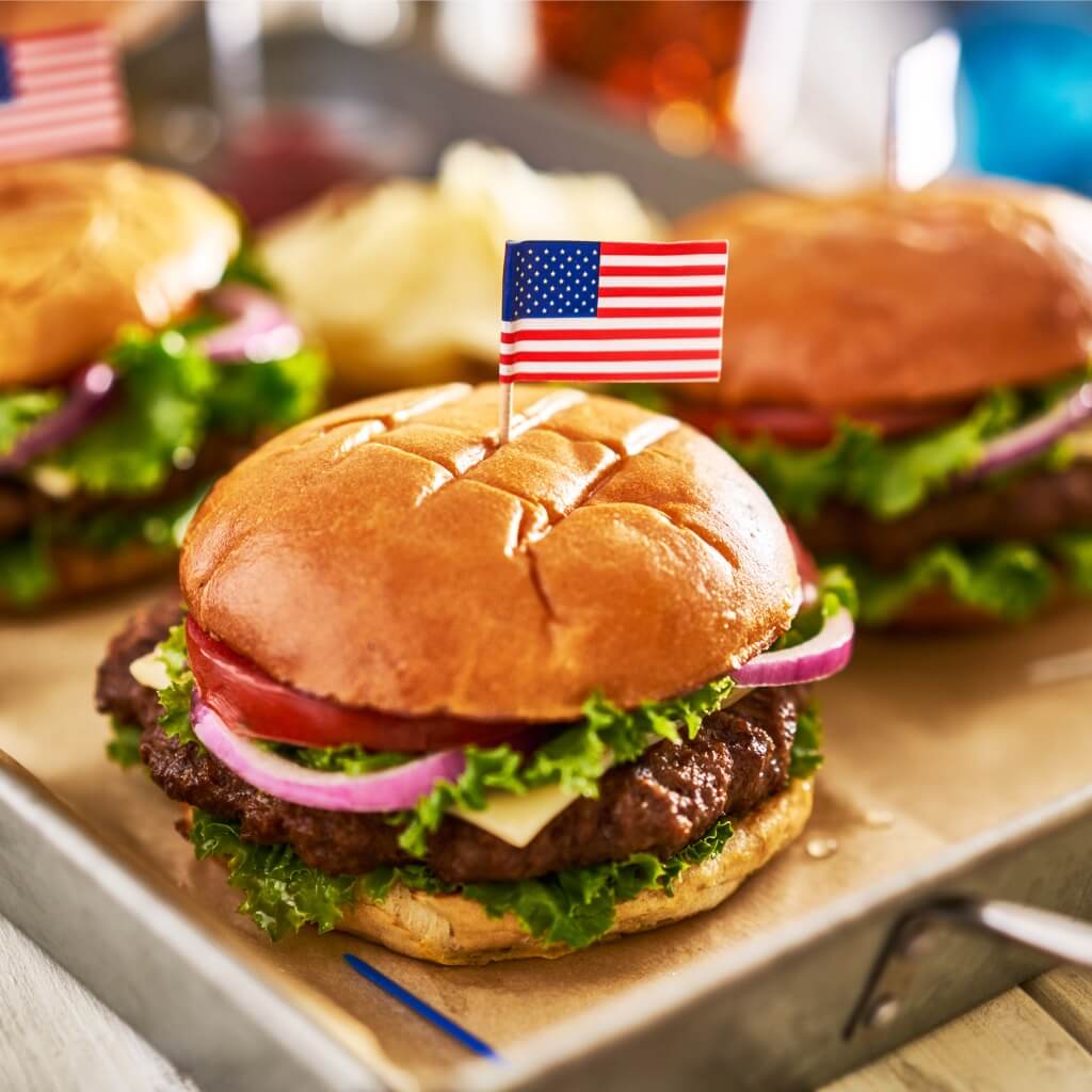 A Veterans Day dinner photo of a hamburger with an American flag toothpick stuck into it.