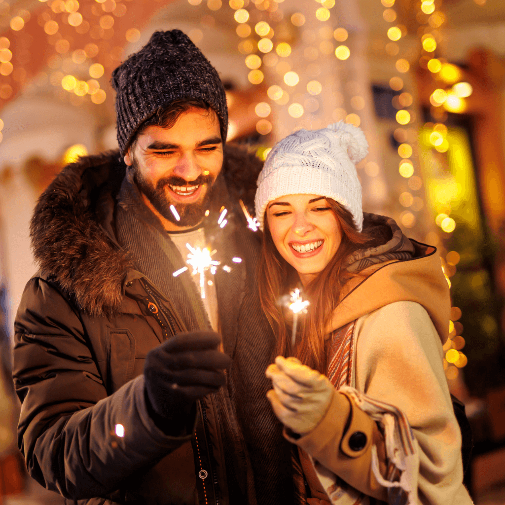 Happy couple holding a sparkler and celebrating new year, new you!