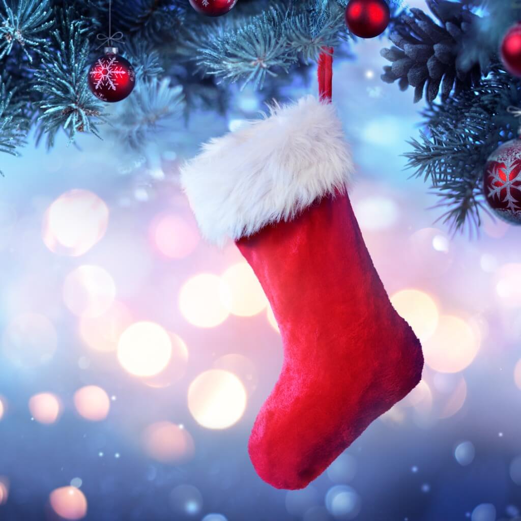 A stocking hanging on a holiday tree with bokeh lights in the background.